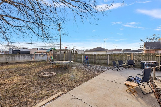 view of yard with a trampoline, a fire pit, and a patio area