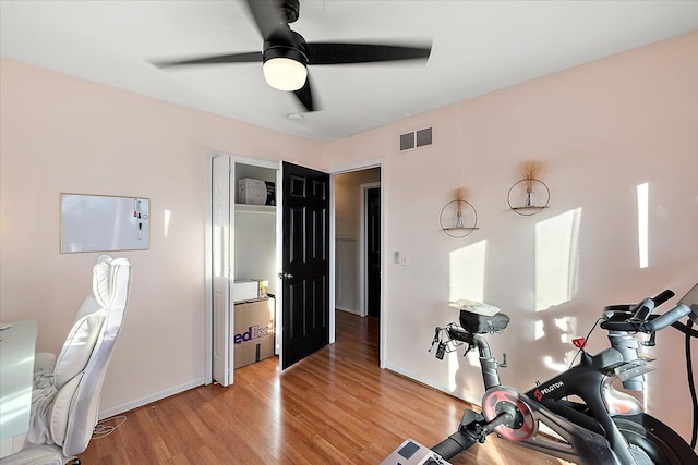 exercise room with light hardwood / wood-style floors and ceiling fan