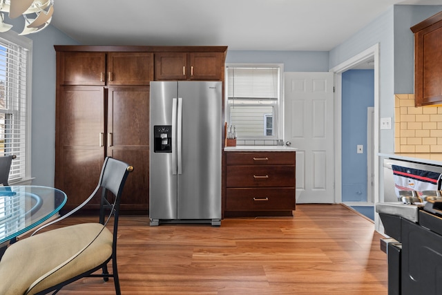 kitchen featuring light hardwood / wood-style floors, stainless steel fridge with ice dispenser, and backsplash