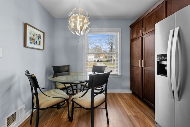 dining space with a notable chandelier and light hardwood / wood-style floors