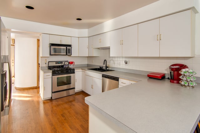 kitchen featuring light hardwood / wood-style floors, decorative backsplash, sink, white cabinetry, and stainless steel appliances