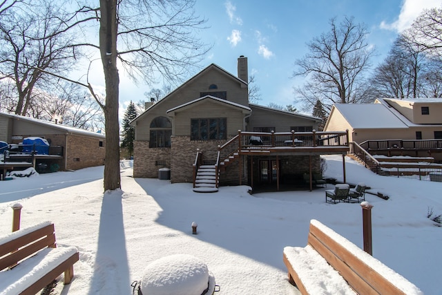 snow covered back of property with a deck