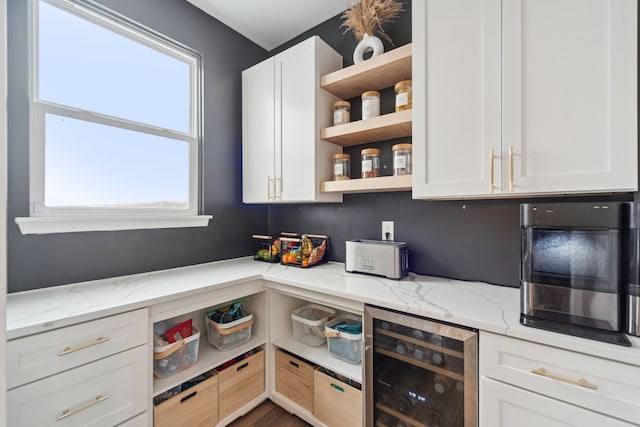 kitchen featuring white cabinetry, a wealth of natural light, light stone counters, and beverage cooler