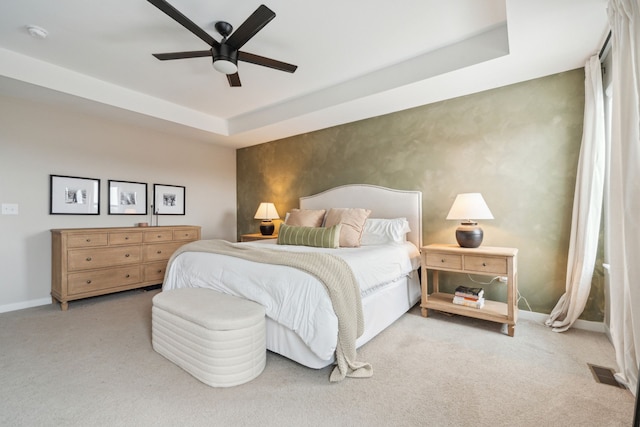 carpeted bedroom featuring a raised ceiling and ceiling fan