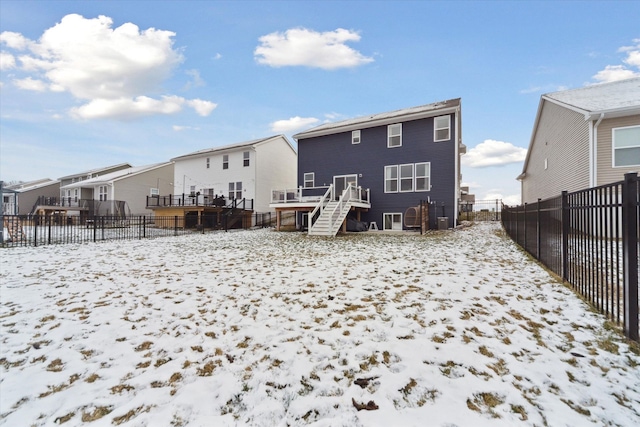 snow covered back of property with cooling unit and a deck