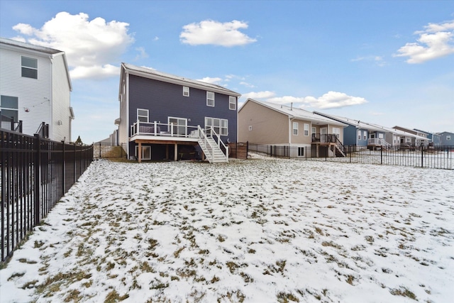 snow covered back of property with a wooden deck