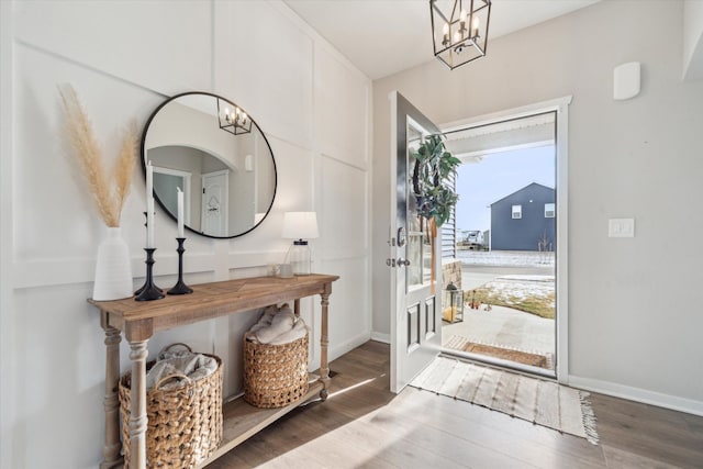 entryway featuring dark wood-type flooring and an inviting chandelier