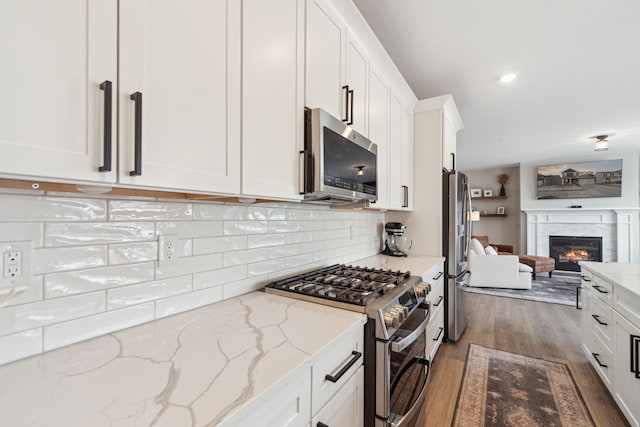 kitchen featuring light stone countertops, dark hardwood / wood-style flooring, white cabinets, and appliances with stainless steel finishes