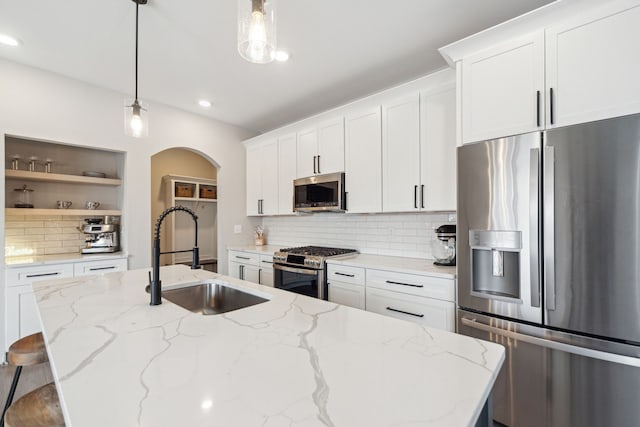 kitchen with pendant lighting, white cabinets, light stone countertops, and stainless steel appliances