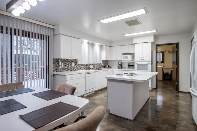 kitchen featuring white appliances, sink, a kitchen island, and white cabinetry