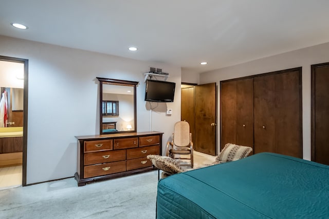 carpeted bedroom featuring ensuite bath and two closets