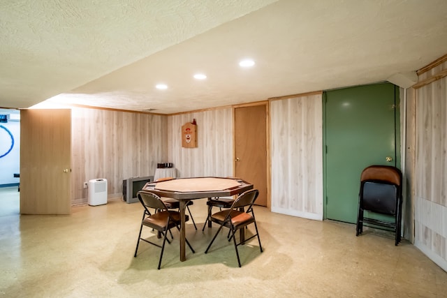 dining room featuring a textured ceiling and wood walls