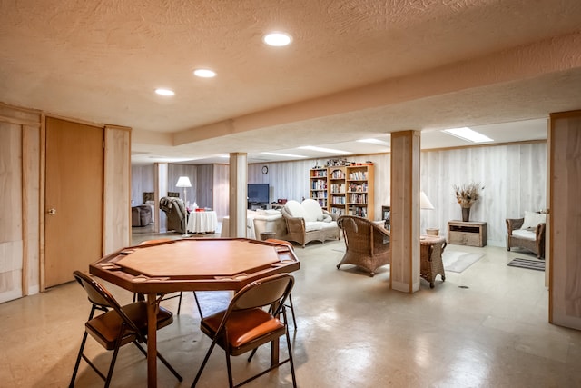 dining space with wooden walls and a textured ceiling