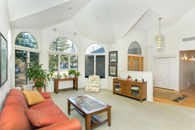 living room with light carpet, high vaulted ceiling, and an inviting chandelier