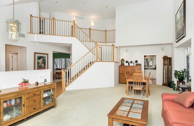 carpeted living room featuring a high ceiling and an inviting chandelier