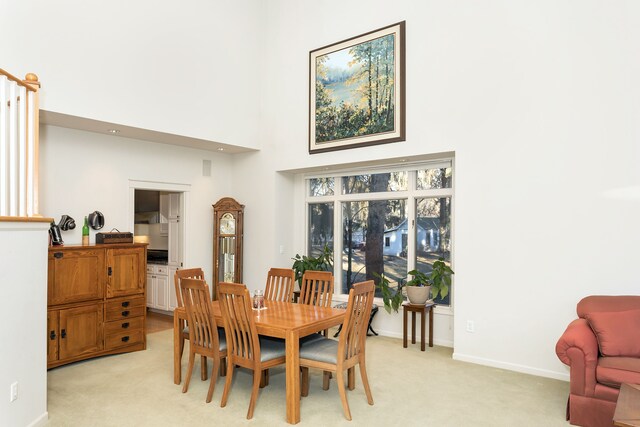 dining area featuring light colored carpet and a towering ceiling