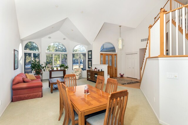 carpeted dining area featuring high vaulted ceiling