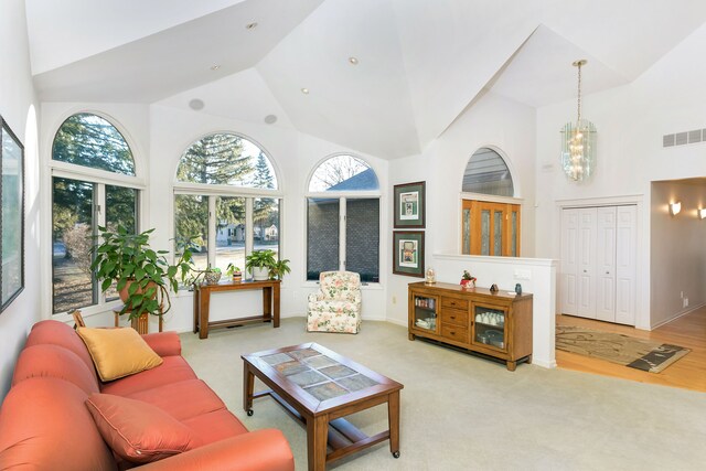 living room with light carpet, high vaulted ceiling, and a notable chandelier