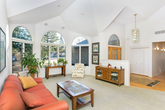 living room featuring a chandelier, light colored carpet, and high vaulted ceiling