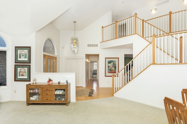 carpeted entryway with high vaulted ceiling