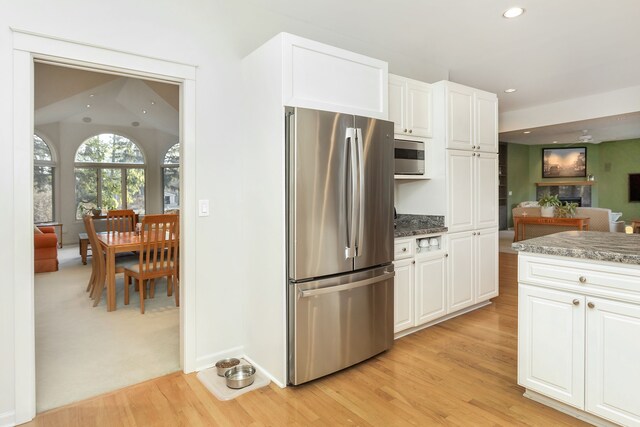 kitchen featuring dark stone counters, white cabinetry, light hardwood / wood-style flooring, and stainless steel appliances