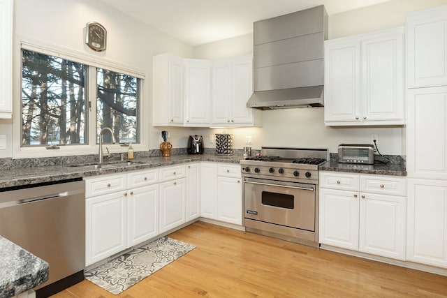 kitchen featuring white cabinetry, sink, wall chimney exhaust hood, stainless steel appliances, and light hardwood / wood-style floors