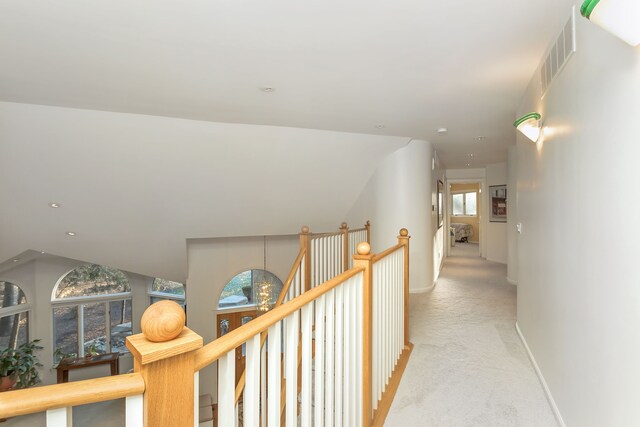 corridor with light colored carpet and a notable chandelier