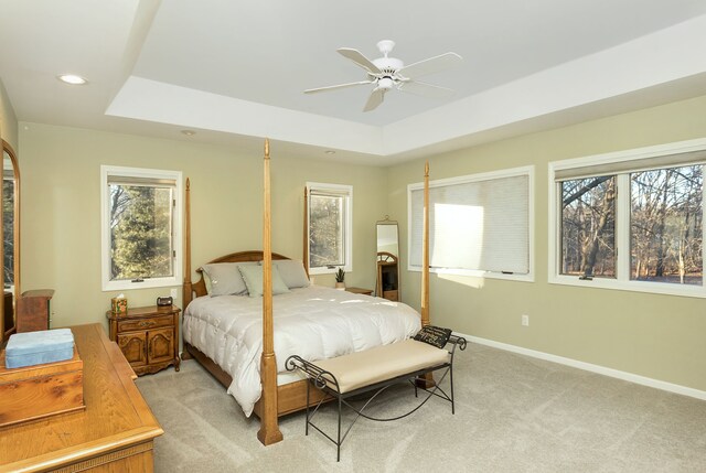 carpeted bedroom with a raised ceiling and ceiling fan