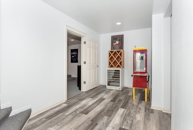 interior space with wine cooler, wood-type flooring, and bar area