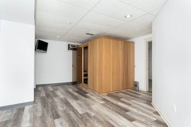 interior space with a drop ceiling and hardwood / wood-style floors