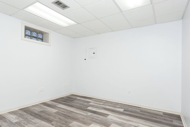 spare room with a paneled ceiling and hardwood / wood-style flooring