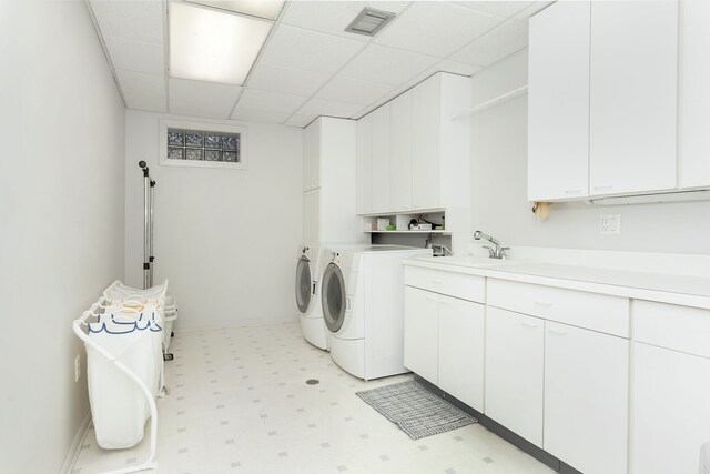 clothes washing area featuring cabinets, washer and clothes dryer, and sink