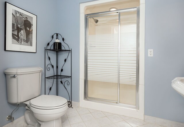 bathroom featuring tile patterned floors, toilet, and a shower with door