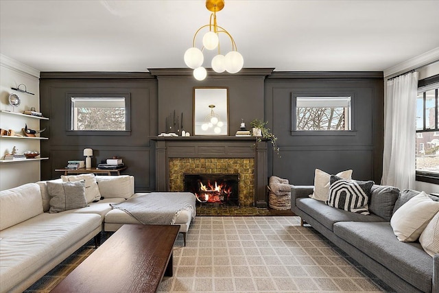 living room with a tiled fireplace, an inviting chandelier, and crown molding