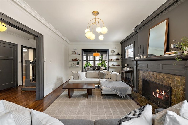 living room with ornamental molding, a chandelier, hardwood / wood-style floors, and a fireplace