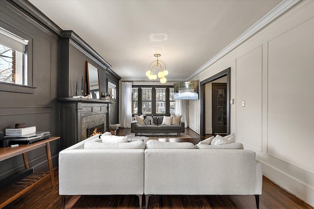 living room featuring ornamental molding, dark hardwood / wood-style flooring, a chandelier, and a fireplace