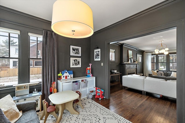 recreation room featuring a notable chandelier, dark wood-type flooring, and crown molding