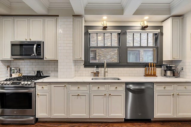 kitchen with sink, appliances with stainless steel finishes, white cabinets, decorative backsplash, and beam ceiling