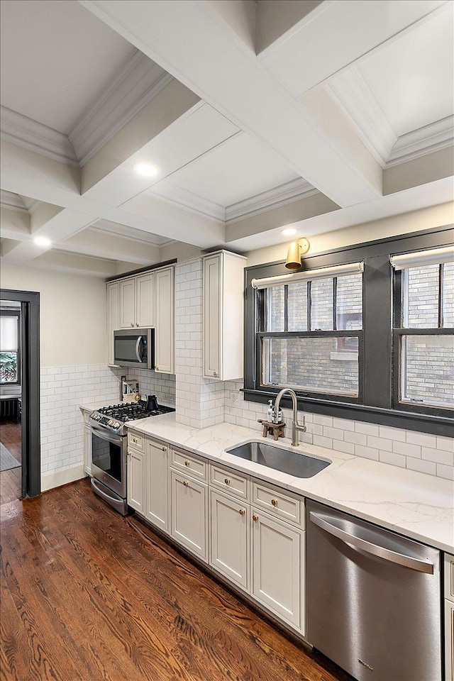 kitchen featuring coffered ceiling, appliances with stainless steel finishes, dark wood-type flooring, light stone counters, and sink