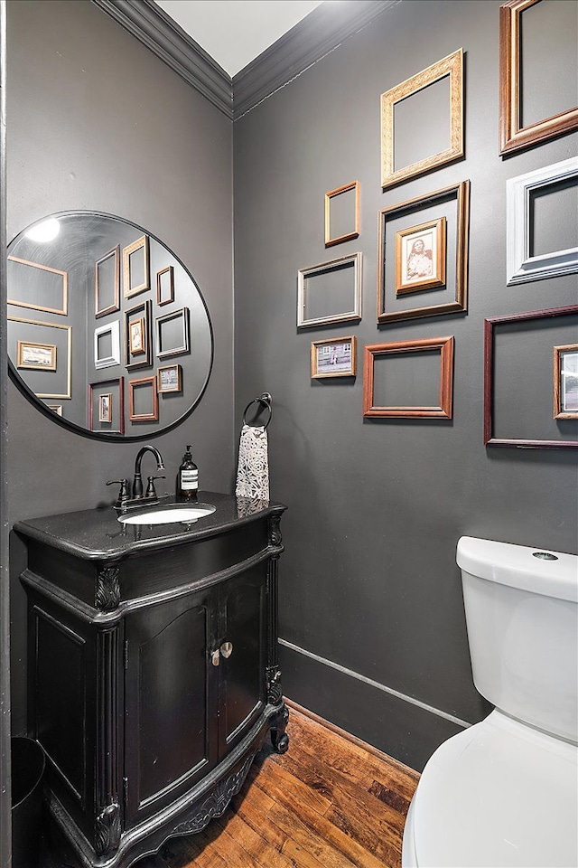 bathroom featuring toilet, vanity, ornamental molding, and hardwood / wood-style floors