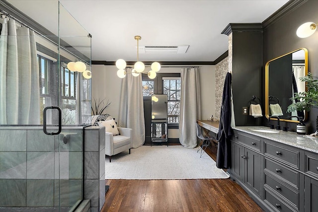 bathroom featuring hardwood / wood-style flooring, a shower with shower door, crown molding, and vanity