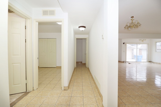 hall with an inviting chandelier and light tile patterned flooring