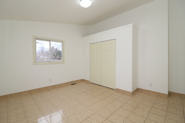 unfurnished bedroom featuring a closet, light tile patterned flooring, and lofted ceiling