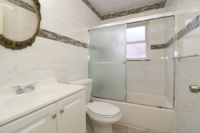 full bathroom featuring toilet, vanity, tile walls, and combined bath / shower with glass door