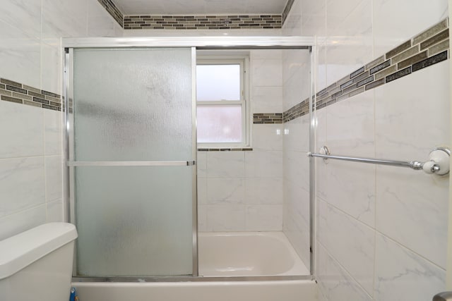 bathroom with toilet and bath / shower combo with glass door