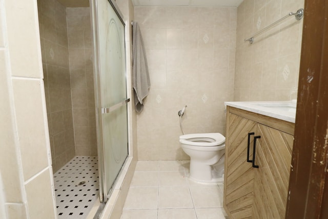 bathroom with vanity, tile patterned flooring, toilet, tile walls, and a shower with shower door