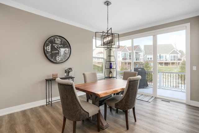 dining space with hardwood / wood-style floors, crown molding, and a chandelier