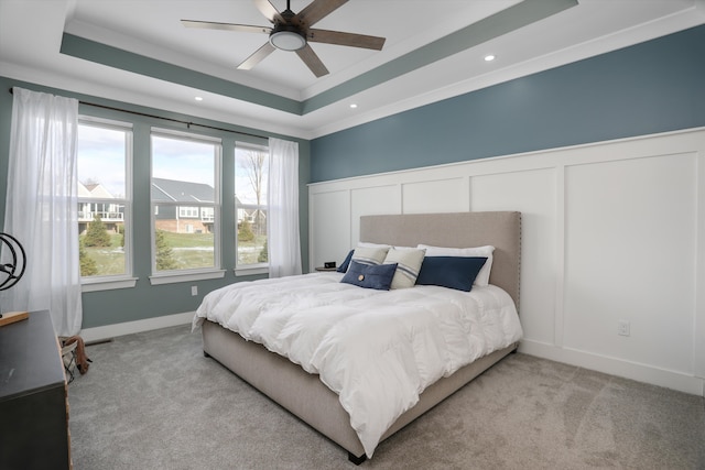 carpeted bedroom featuring a tray ceiling, ceiling fan, and crown molding