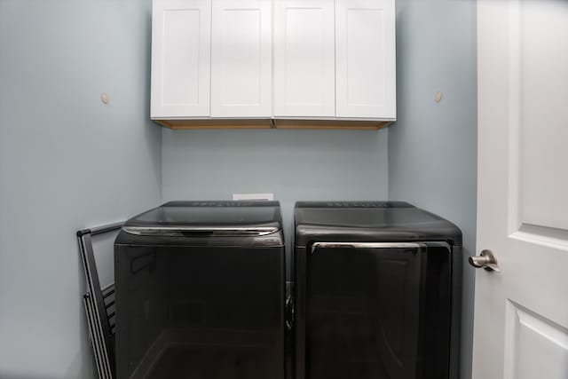 laundry room featuring washer and clothes dryer and cabinets