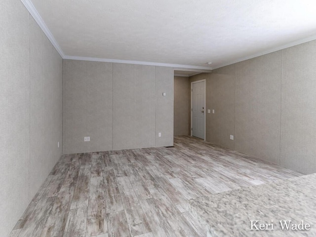 empty room with crown molding and light hardwood / wood-style floors